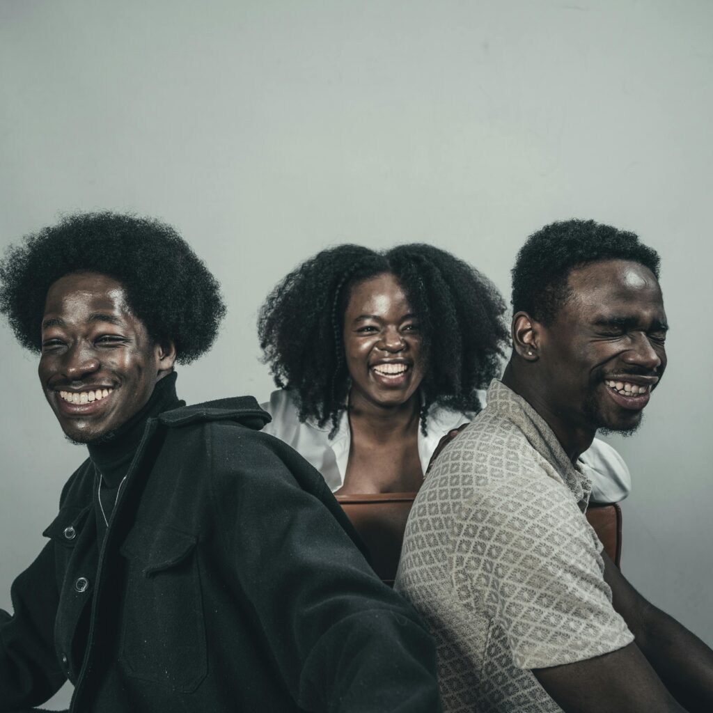 A trio of friends smiling and enjoying a great time indoors. Their happiness is contagious.